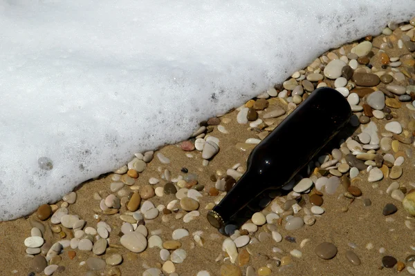 Bottle on sand near water — Stock Photo, Image