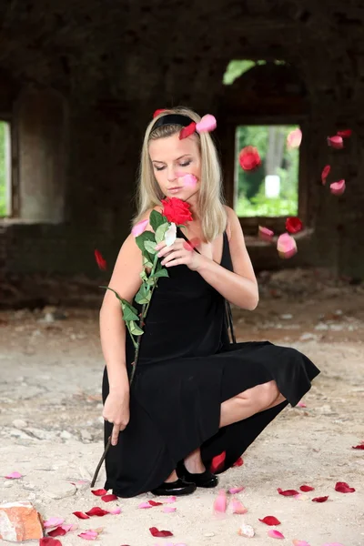 Donna con rosa sotto petali cadenti — Foto Stock