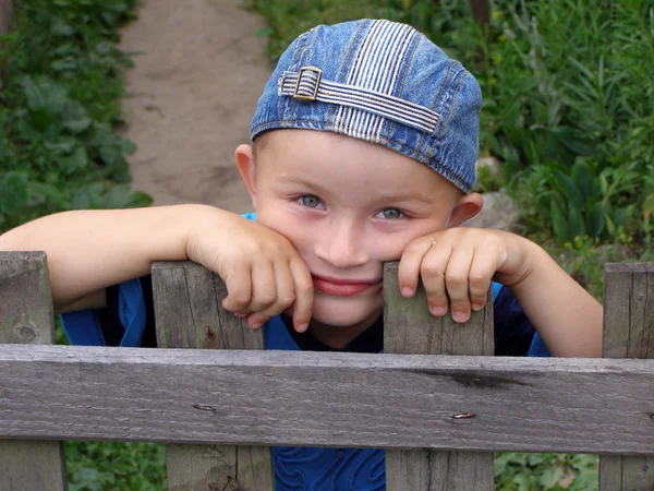 Kleine jongen leunde tegen het hek — Stockfoto