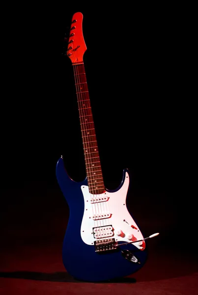 Elektrische gitaar in ray van rood licht — Stockfoto