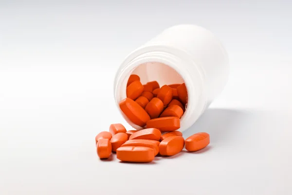 Orange piller spildes fra flaske - Stock-foto