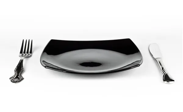 Üres fekete tányér kést és a villát — Stock Fotó