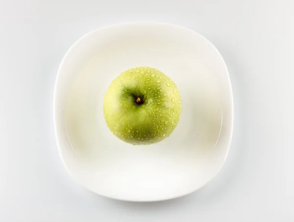 Zelené jablko na bílé nádobí — Stock fotografie
