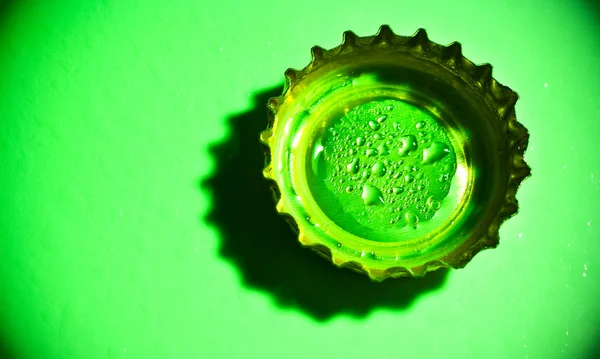 Tampa de cerveja com gotas de água no verde — Fotografia de Stock