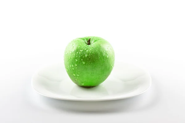 Πράσινο μήλο σε λευκό πιάτο — Φωτογραφία Αρχείου