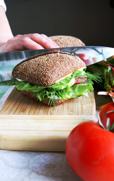 Housewife divides healthy rye bread sand — Stock Photo, Image