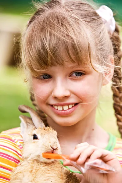 Happy girl feed rabbit with carrot. — Stock Photo, Image
