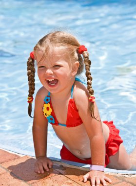 Child girl near blue swimming pool