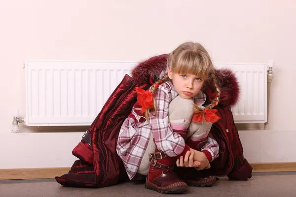 Chica con abrigo cerca del radiador. Crisis. . — Foto de Stock