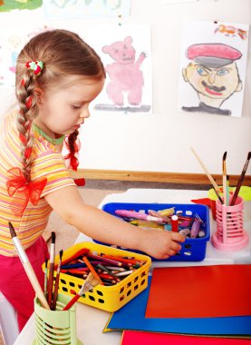 Child with colour pencil in play room. clipart