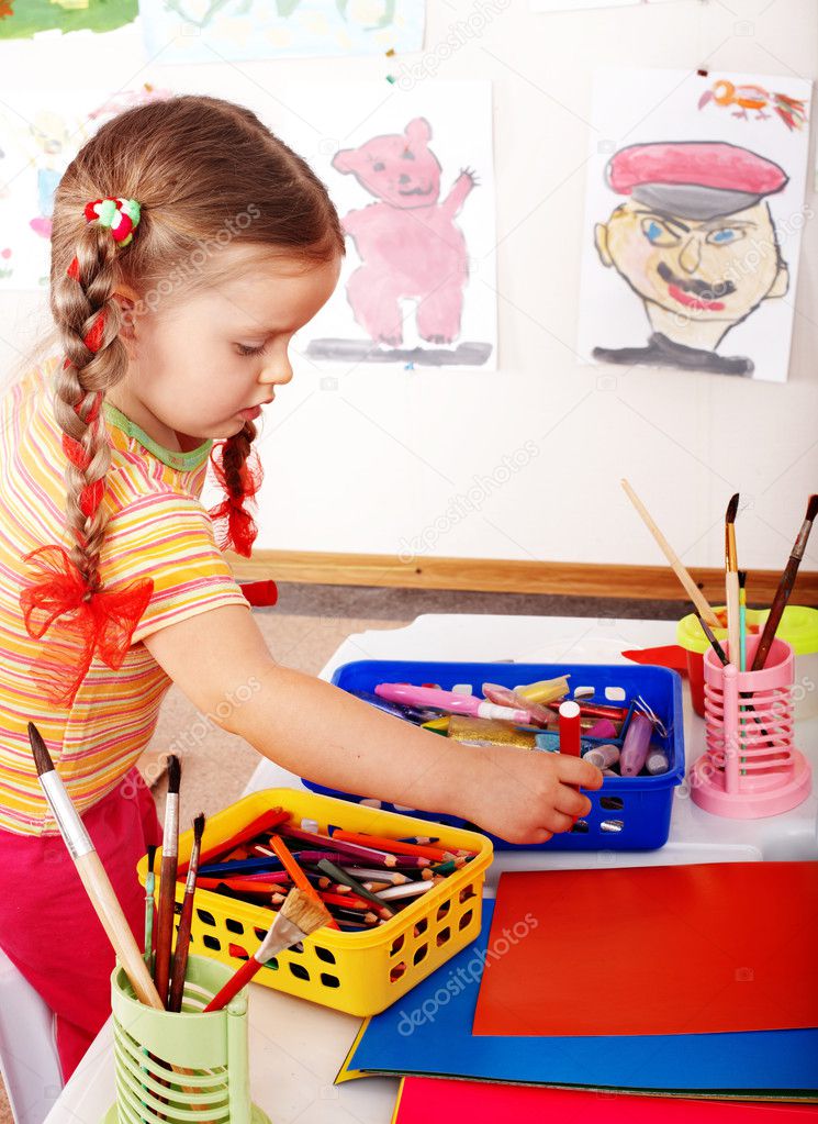 Child with colour pencil in play room.