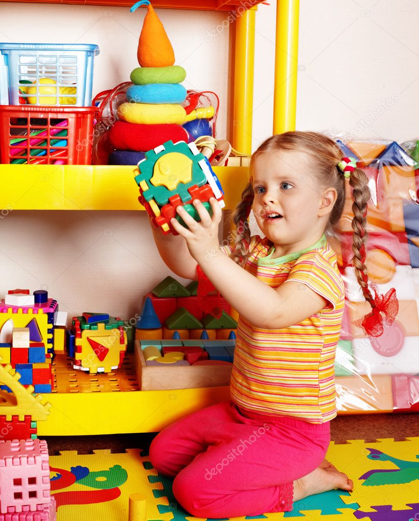 Child with puzzle and block in playroom