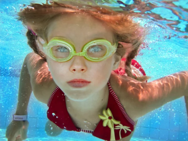 Kind meisje onderwater zwemmen in zwembad. — Stockfoto