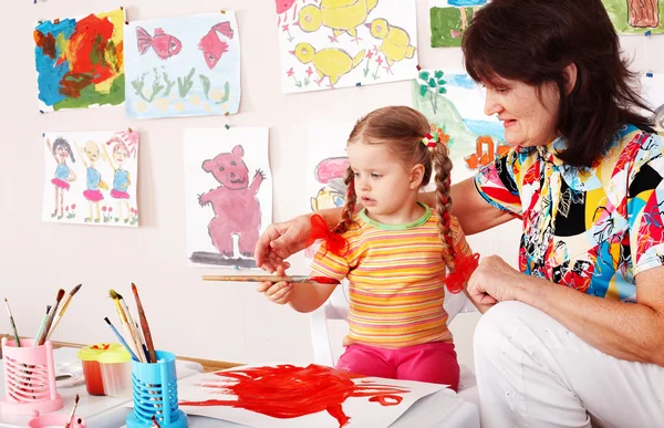 Ребенок с учителем рисует краски — стоковое фото
