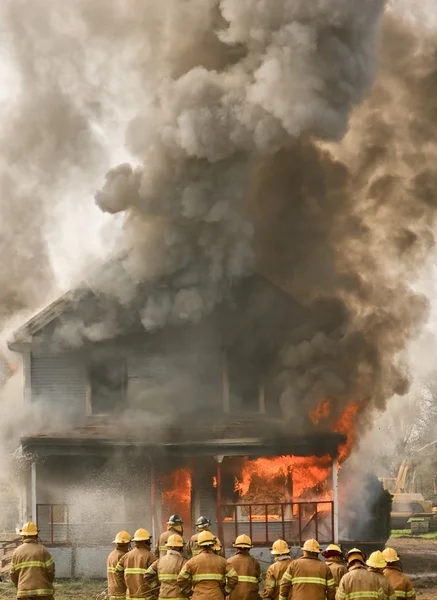 Bomberos en una casa en llamas — Foto de Stock