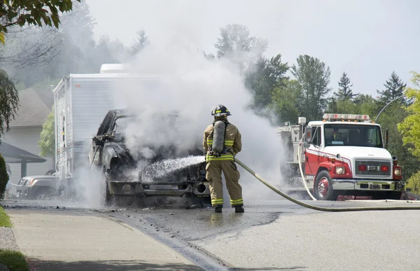 Brandweerman blusmiddelen brandende voertuig — Stockfoto