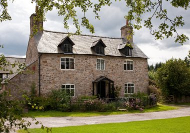 Old stone cottage surrounded by trees an clipart