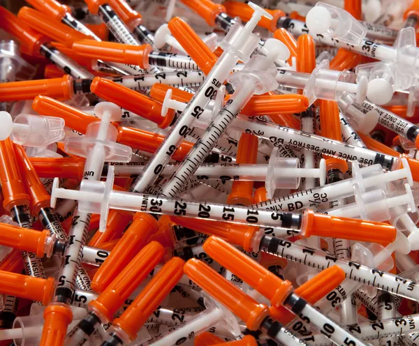 Comprimido de seringas usadas com tampas laranja — Fotografia de Stock