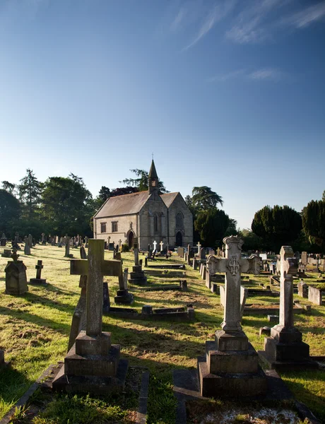 Sidelit view of graveyard with church — Stock Photo, Image