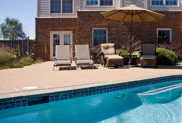 Achtertuin zwembad met stoelen en parasol — Stockfoto