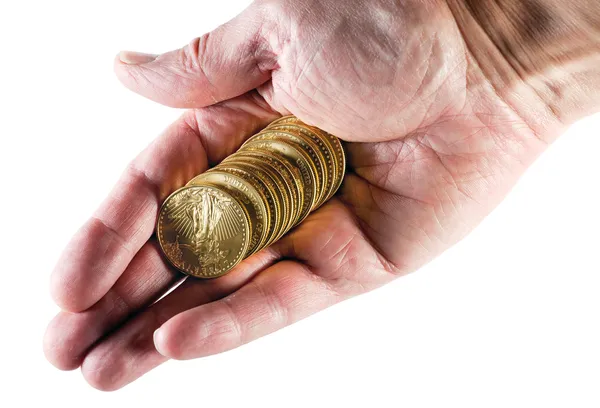 Stack av tio guld mynt i handen — Stockfoto
