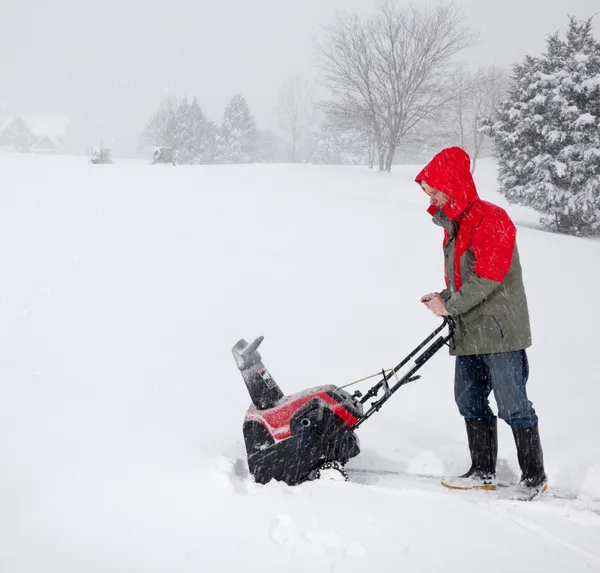 Hombre usando soplador de nieve en la unidad nevada — Foto de Stock