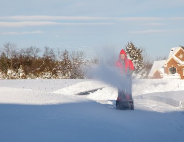 Man using snow blower on snowy drive clipart