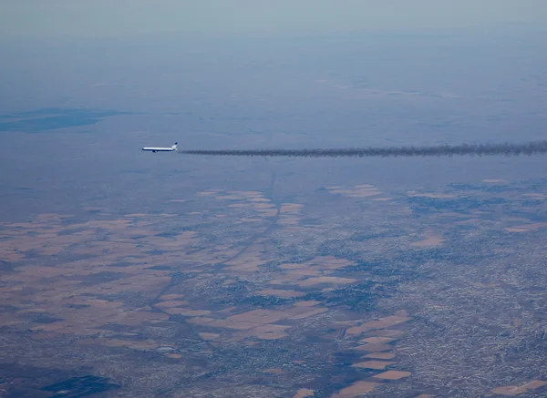 Авиалайнер с длинным дымовым шлейфом — стоковое фото