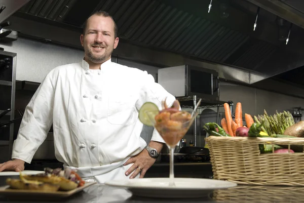 Улыбающийся шеф-повар с овощами и креветками — стоковое фото