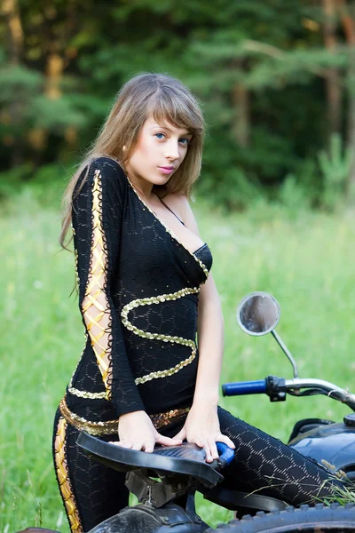 Jonge vrouwen met zwarte motorfiets. — Stockfoto