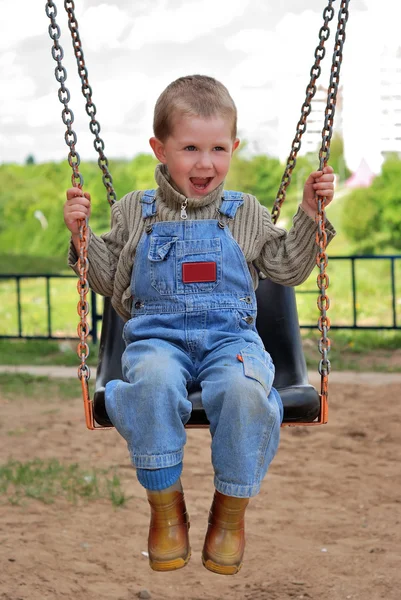 Мальчик играет на качелях — стоковое фото