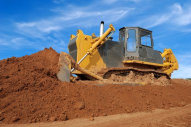 Heavy bulldozer moving sand in sandpit clipart
