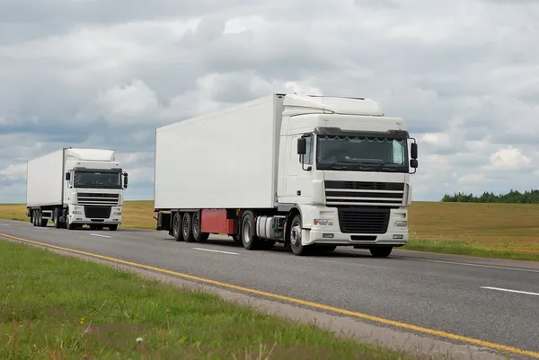 Пара белых грузовиков на шоссе — стоковое фото