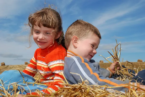 Två leende barn i halm utomhus — Stockfoto