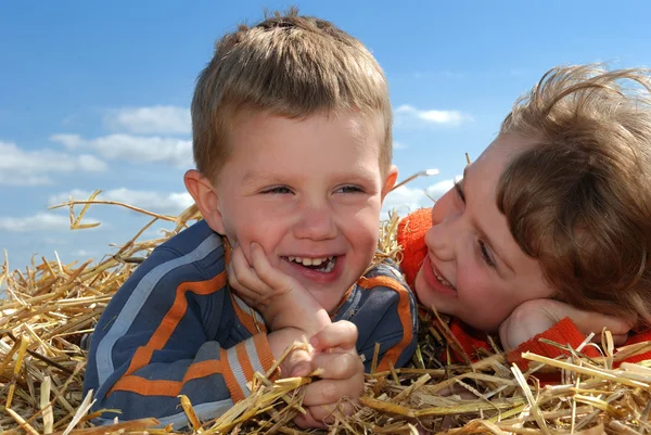 Smiling boy and girl in straw outdoors c — Stock Photo, Image