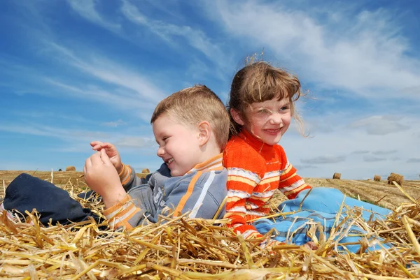 Sorrindo menino e menina na palha ao ar livre — Fotografia de Stock