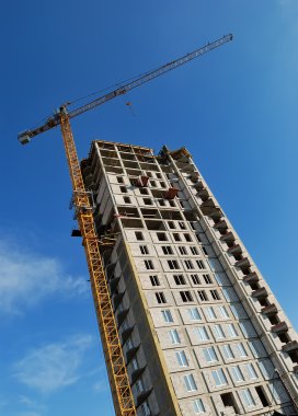 Yellow tower crane at multistory buildin clipart