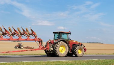 Tractor moving plough on the road clipart