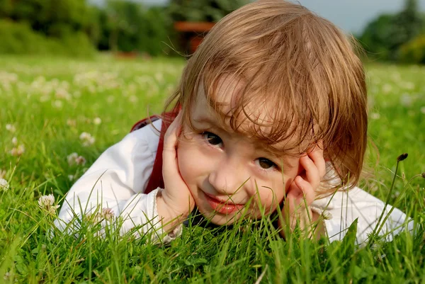 Närbild lilla flicka på det gröna gräset — Stockfoto