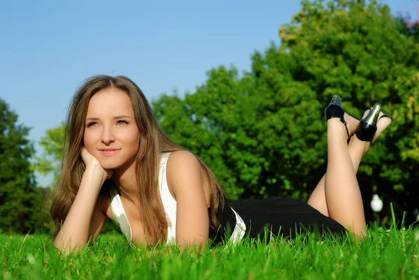 Flicka avkopplande utomhus liggande på gras — Stockfoto