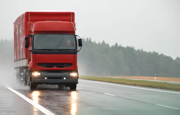 Красный грузовик на мокрой дороге — стоковое фото