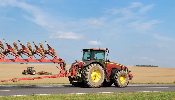 Traktorn flyttar plog på vägen — Stockfoto