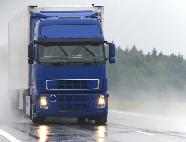 Blauwe vrachtwagen op natte weg — Stockfoto