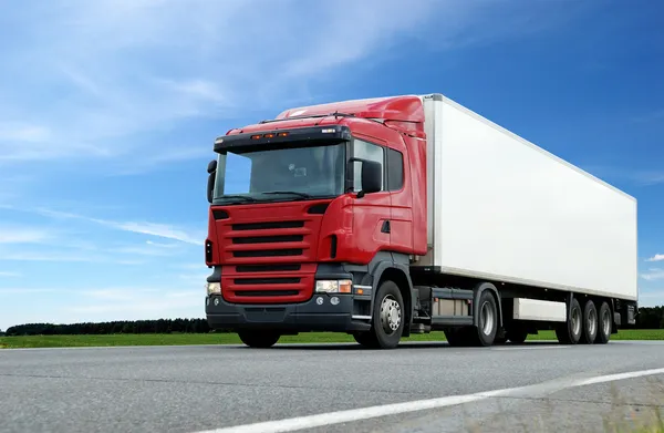 Красный грузовик с белым трейлером над голубыми — стоковое фото