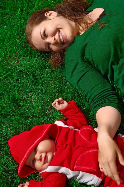 年轻的女孩和她的孩子在绿色草地上 — 图库照片