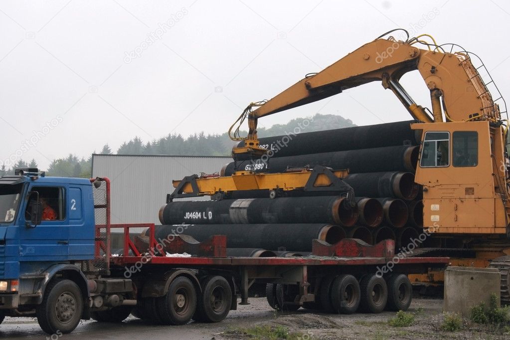 Crane loading pipes in the semi-truck