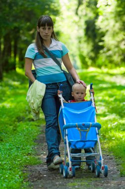 Mother and her son on footpath in park clipart