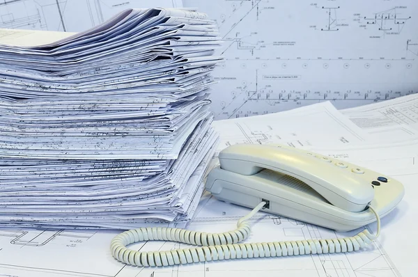 White phone and heap of project drawings — Stock Photo, Image
