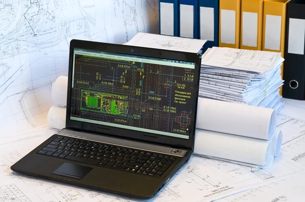 Laptop in der Nähe von Stapel von Projektzeichnungen — Stockfoto