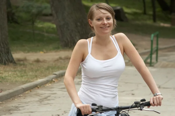 Ung kvindelig ridning smilende cykel - Stock-foto